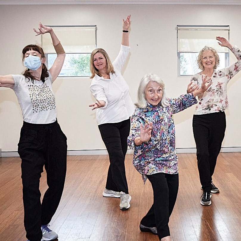 Four women dancing with one arm in the air